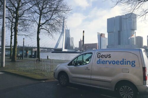 Bestelbus van Geus Diervoeding aan de Maas, met de Erasmusbrug en de Rotterdamse skyline op de achtergrond